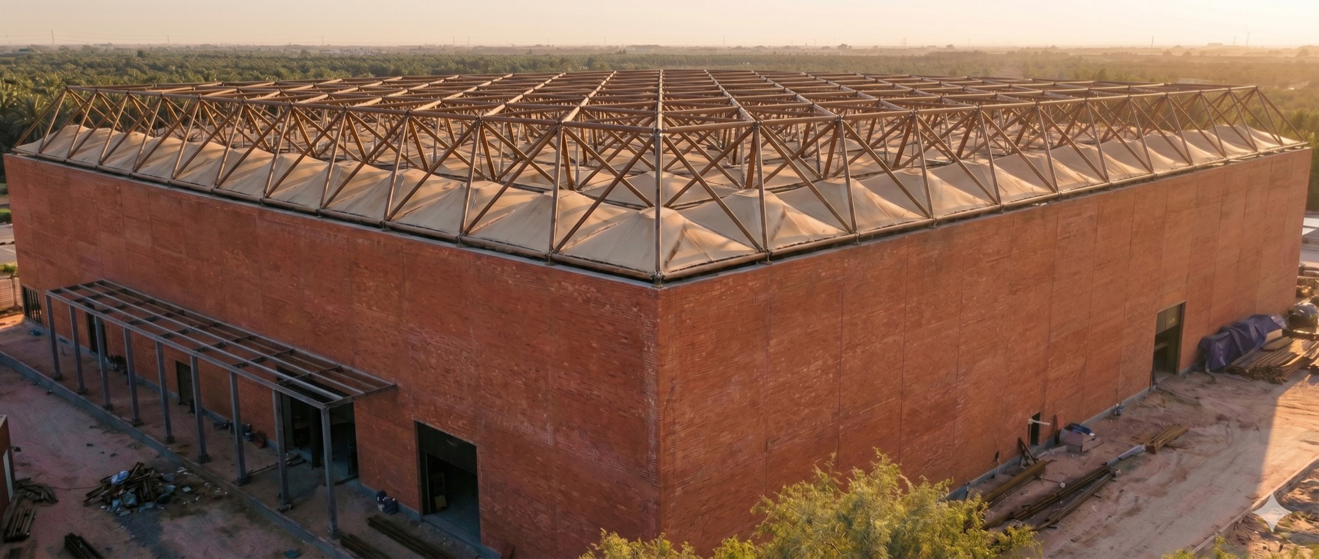 The arena's brick shell and steel space-frame at sunset